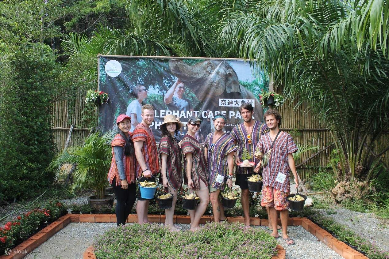 tourists in thai costume posing in front of the elephant care park banner